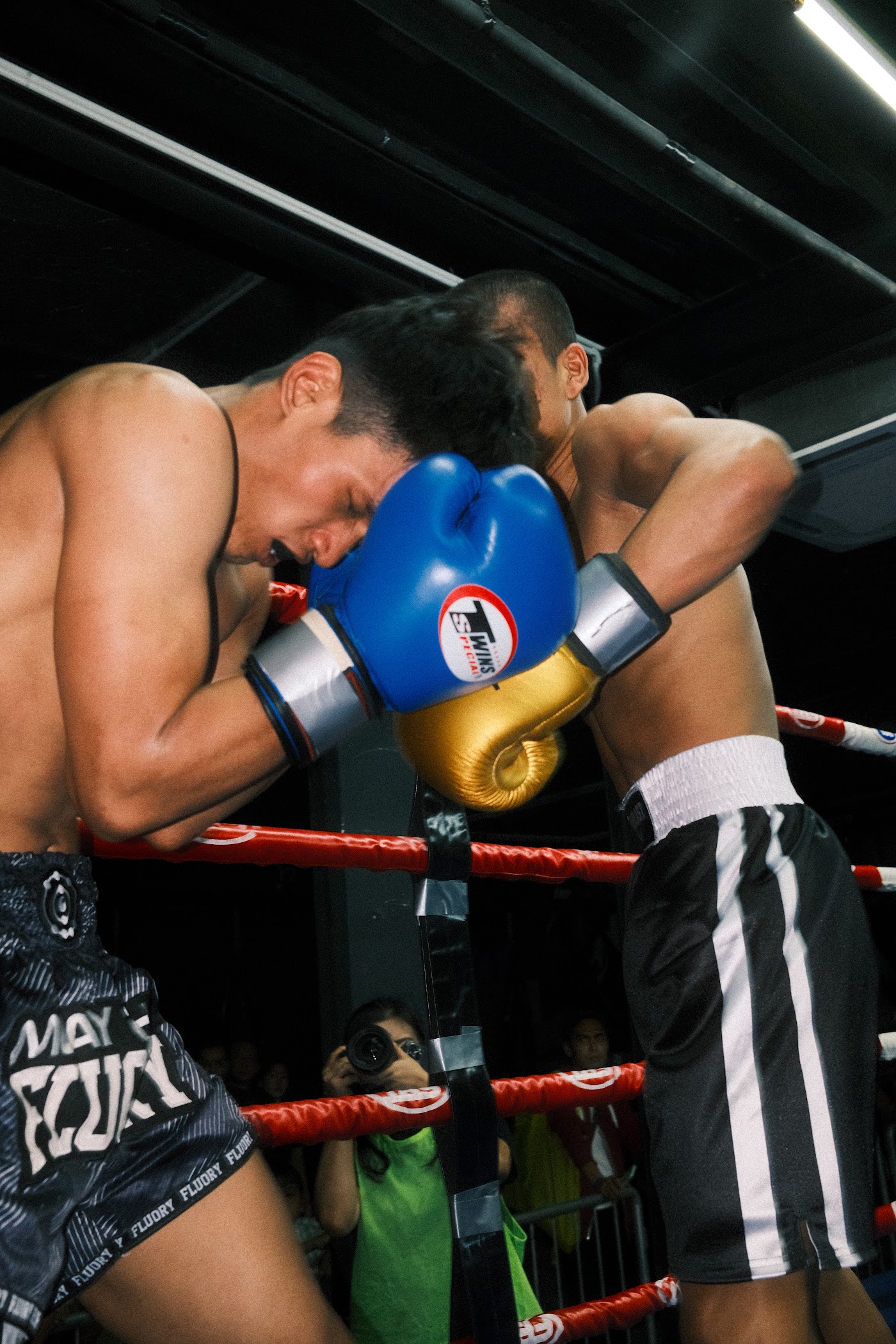 Two fighters locked in a clinch on the ropes